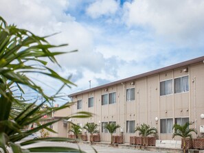A hotel with a flat facade, multiple windows, and outdoor seating. - Hotel Southern Village Okinawa (Kitanakagusuku)
