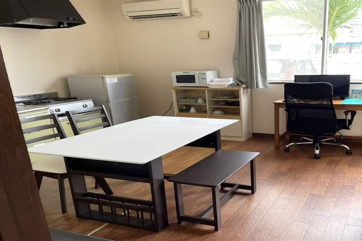 A compact kitchen with a dining table, chairs, a microwave, and a refrigerator.