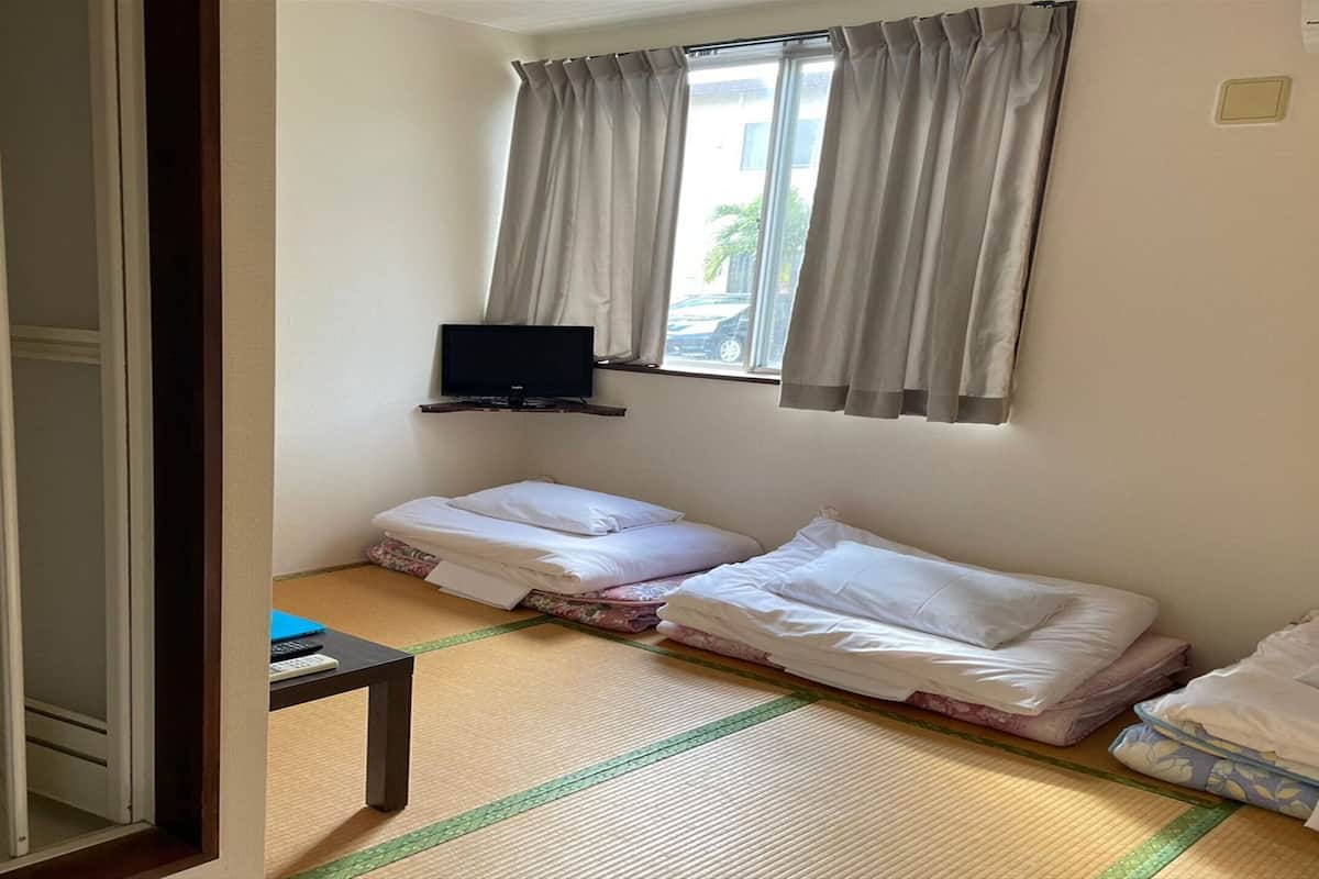 A hotel room with two beds, a TV on the wall, and a small table.
