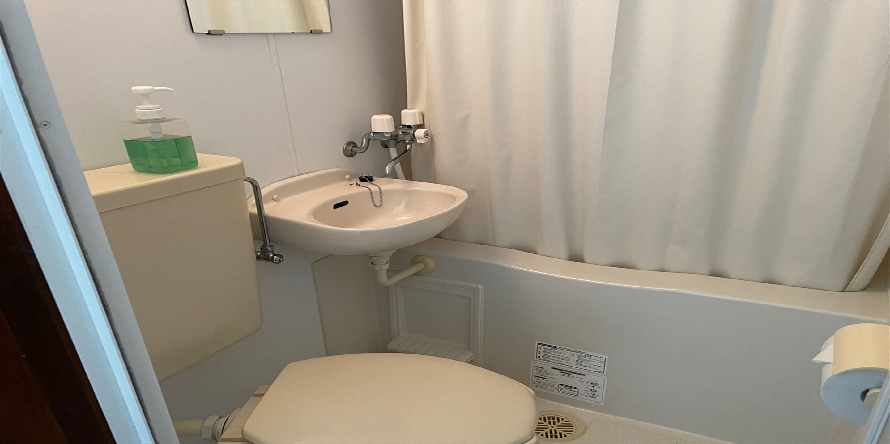 Un baño pequeño con inodoro, lavabo y cortina de ducha.