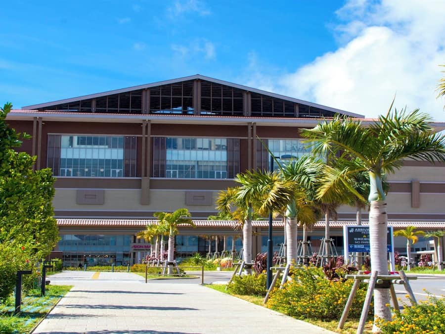 A modern building with a flat roof, large windows, and a covered entrance area.