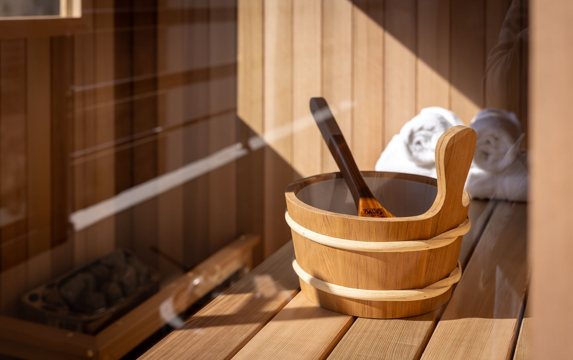 Un cuenco de madera con una cuchara, sobre una plataforma de madera cerca de la zona de sauna.