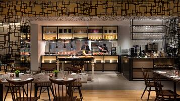 En moderne restaurant med barområde, møbler i træ og et mønstret loft.
