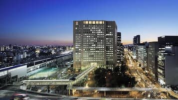 A high-rise building with a grid of windows, surrounded by a busy urban street with multiple lanes and traffic lights.