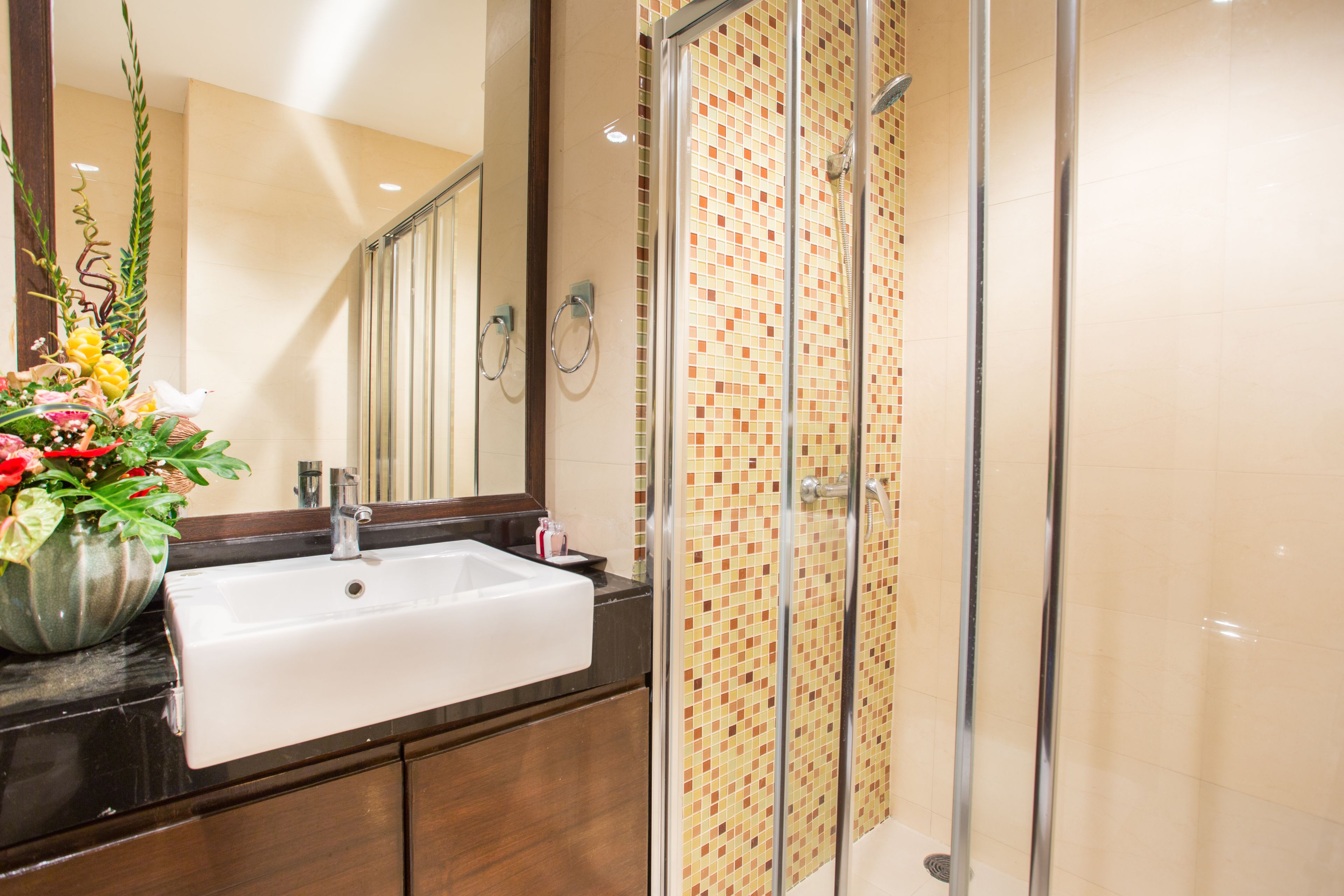 A bathroom with a white sink, a glass shower enclosure, and a mirror.
