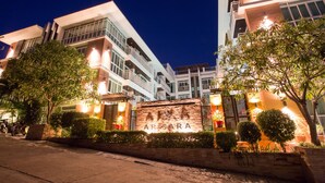 A modern building with a sign reading "ARISARA" at the entrance, surrounded by well-maintained greenery and illuminated by street lighting. - Arisara Place (Koh Samui)