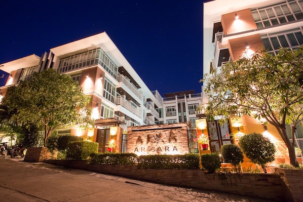 A modern building with a sign reading "ARISARA" at the entrance, surrounded by well-maintained greenery and illuminated by street lighting.