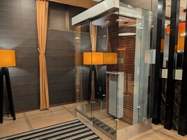 Un ascensor moderno con puertas de vidrio, pared de paneles de madera y alfombra a rayas negras y blancas.
