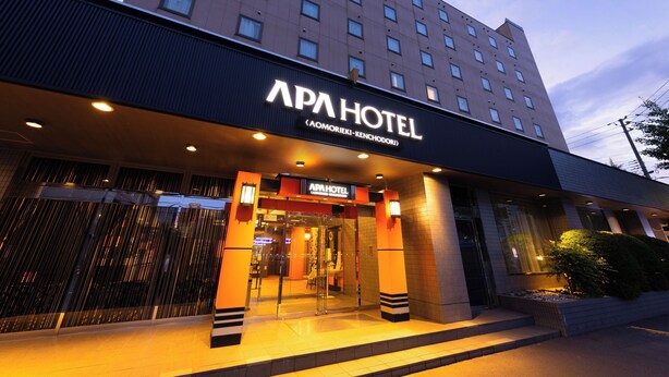 L’extérieur de l’hôtel APA présente un design moderne, avec une entrée imposante et une grande enseigne au-dessus des portes.