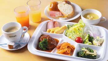 A meal tray with various dishes including pasta, vegetables, and a bread roll. There are also two glasses of orange juice and a cup of coffee.