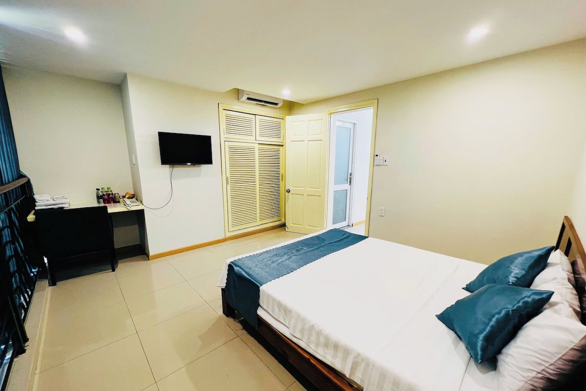 A bedroom with a bed, a desk, a television, and a wardrobe.