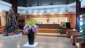A hotel lobby with a Christmas tree, reception desk, and clocks displaying time in various cities. - The Coast Hotel Vung Tau (Ho Chi Minh City)