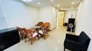 A dining area with a table and chairs, a black sofa, and a refrigerator. - The Coast Hotel Vung Tau (Ho Chi Minh City)