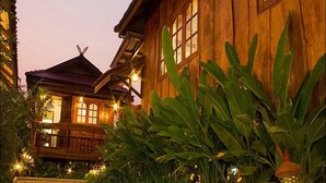 A wooden building with large windows and a balcony, surrounded by lush greenery. - Dang Ky Resort (Cha-am)