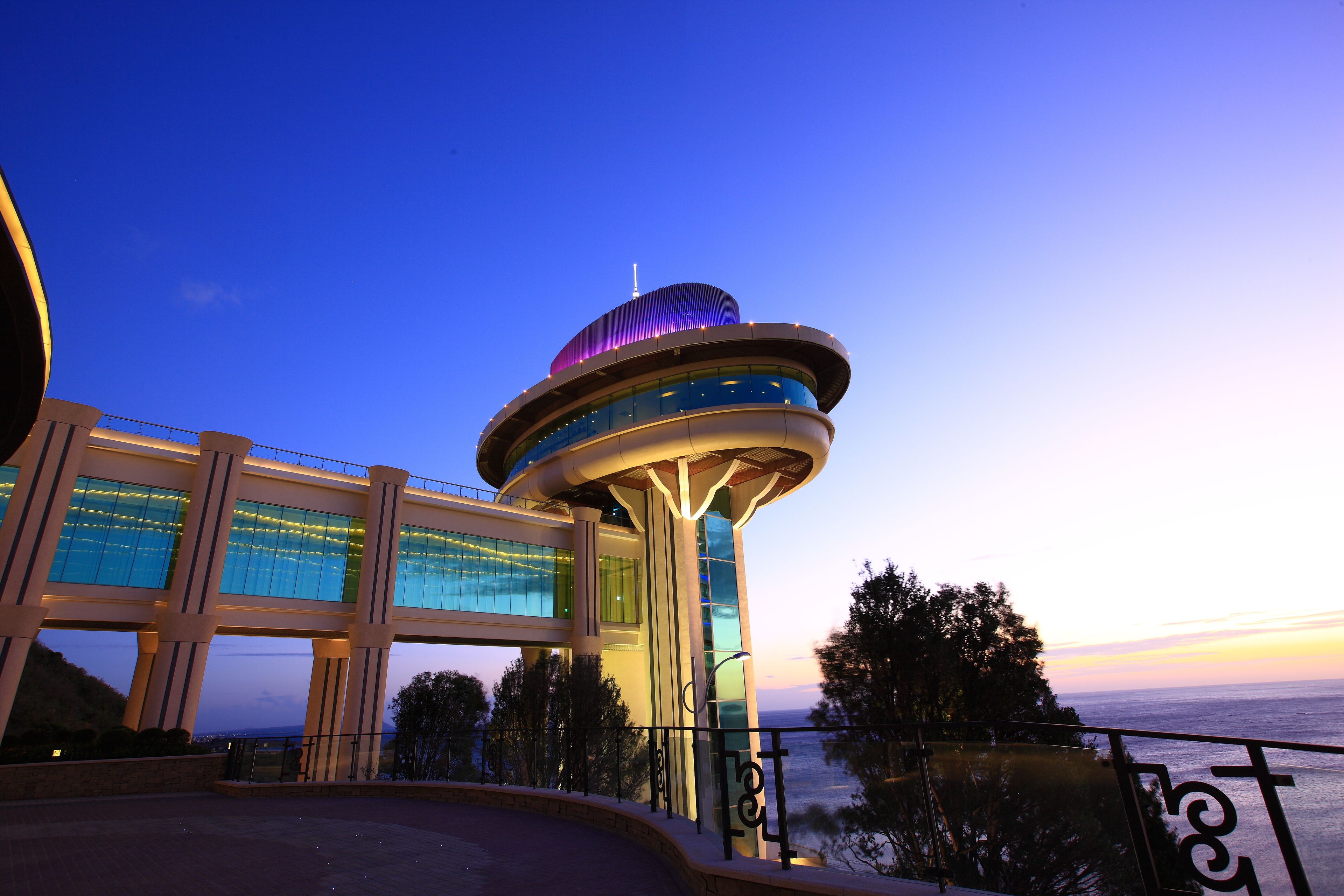 Um edifício moderno com uma torre circular marcante e fachada de vidro.