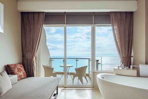 Habitación de hotel con balcón, cama, baño y vista al mar.