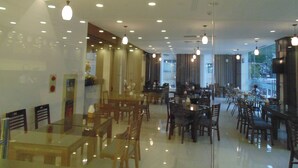 A spacious restaurant with multiple dining areas, including a bar and a seating area with tables and chairs. - Sport Hotel (Hanoi)