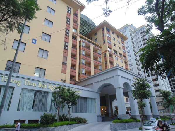 Un edificio de varios pisos con una entrada destacada, ventanas grandes y un letrero que indica que es un hotel.