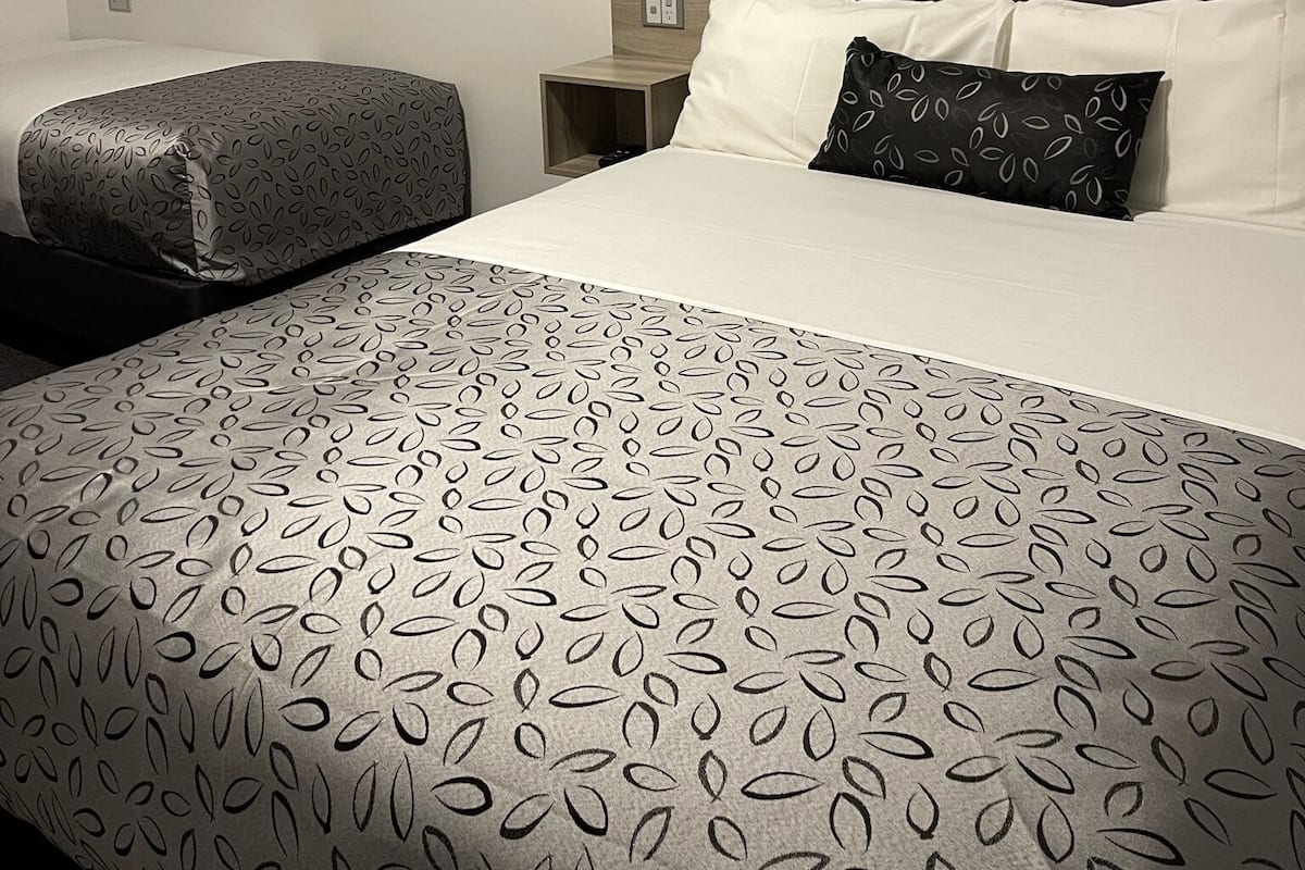 Una habitación de hotel con una cama grande, una mesita de noche, una lámpara de pared y un cuadro de flores de loto.