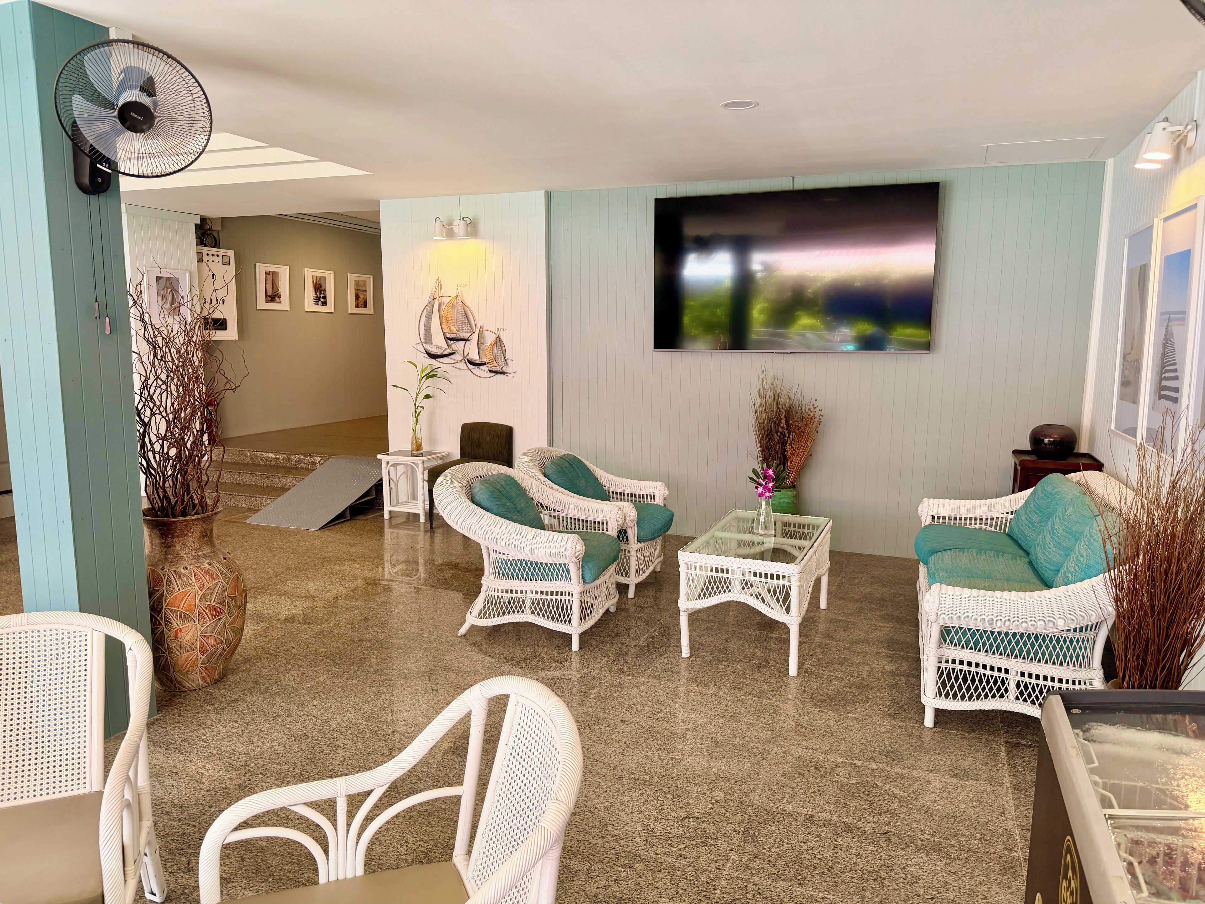 A room with wicker furniture, a flat-screen TV, and a fan.