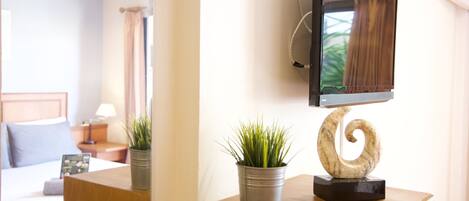 A hotel room with a bed, bedside table, and a TV mounted on the wall.