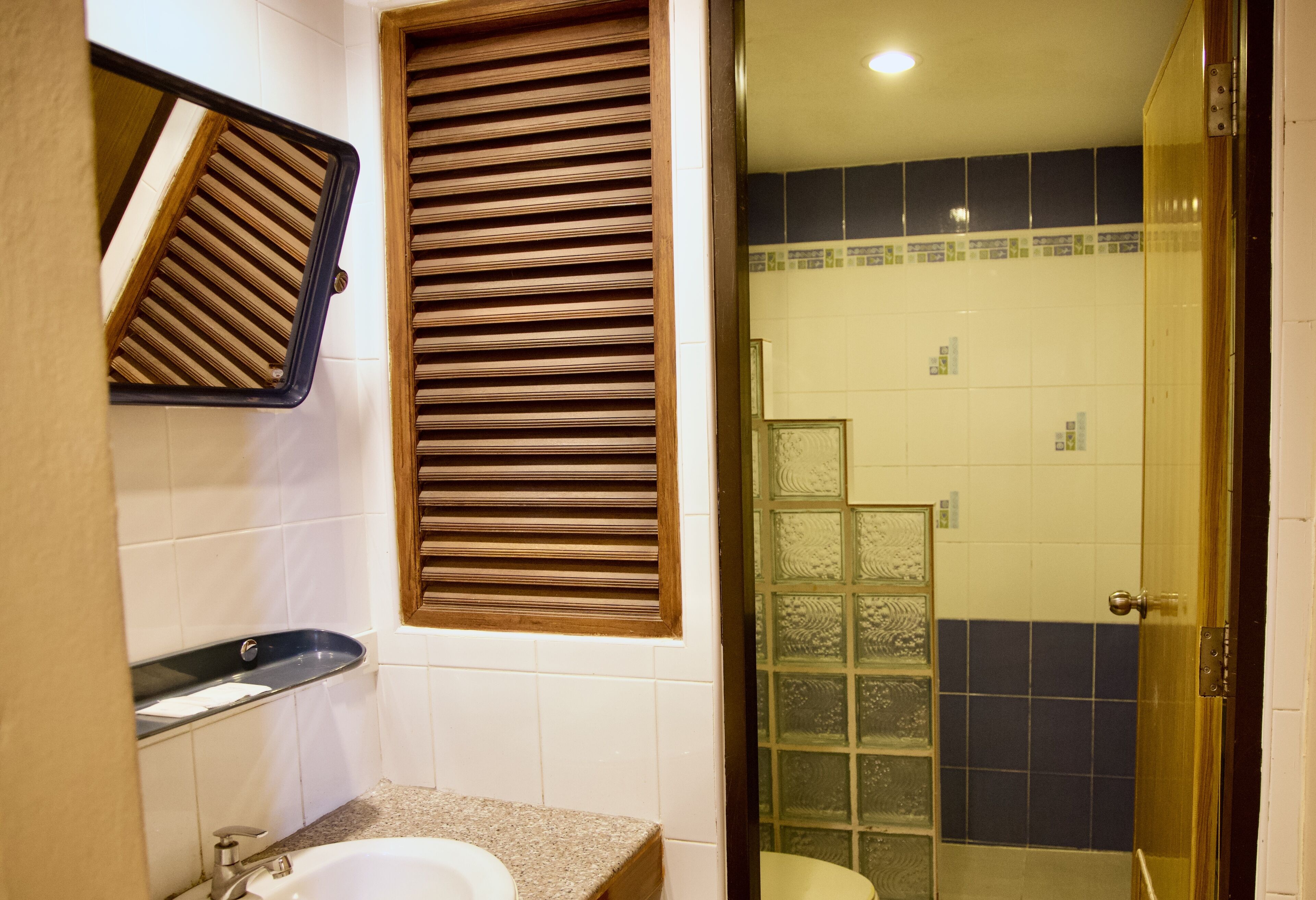 A bathroom with a sink, mirror, and shower area.