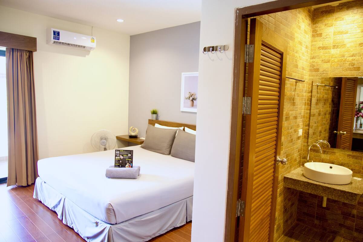 A hotel room with a bed, bedside table, and a small potted plant.