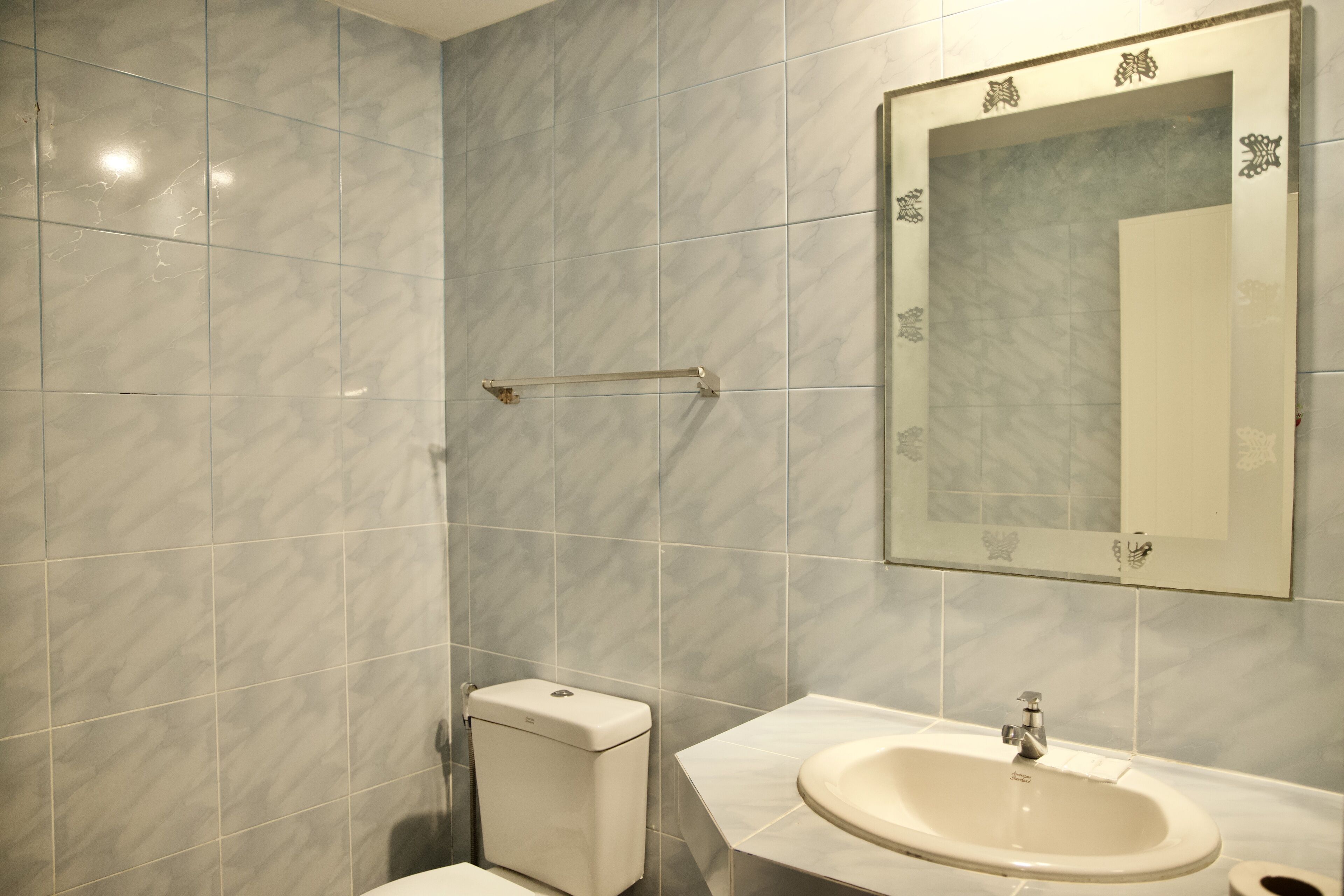 A bathroom with a toilet, sink, and mirror.