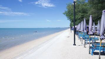 Uma praia com uma fileira de guarda-sóis e bancos ao longo da orla.