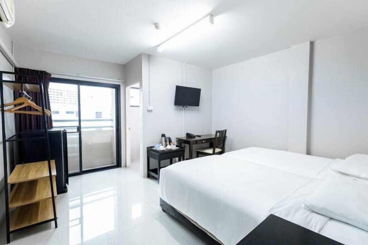 A hotel room with a bed, a desk, a chair, a TV, and a wardrobe.