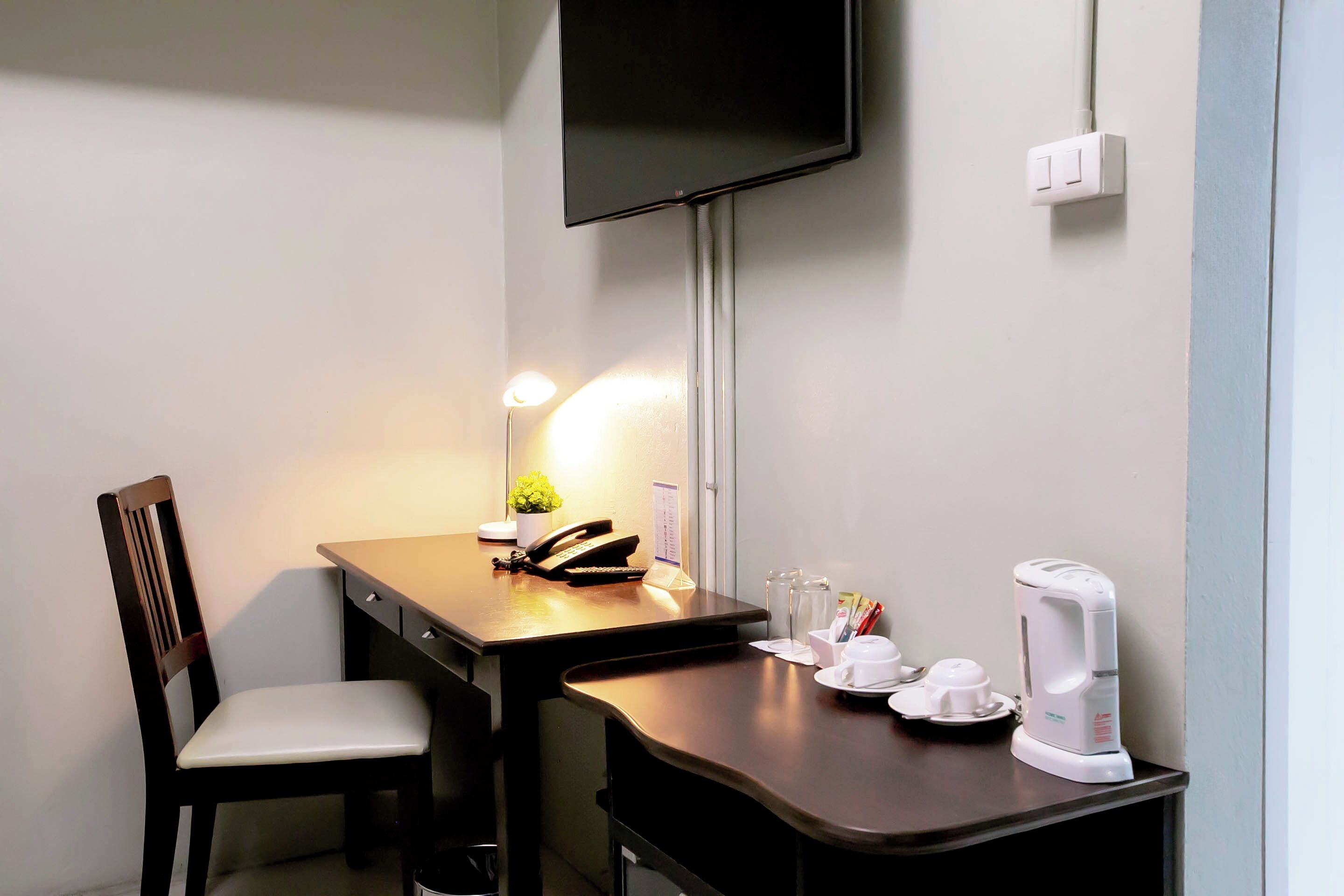 A small, neatly arranged workspace with a desk, chair, and a mounted television.