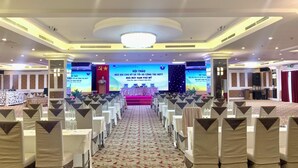 A conference room with rows of chairs facing a stage with a large screen displaying text. - Petro Hotel (Ho Chi Minh City)