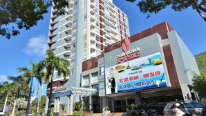 A modern hotel with multiple floors, a prominent signboard advertising hotlines and golf, and a well-maintained entrance area with cars and motorcycles parked. - Petro Hotel (Ho Chi Minh City)