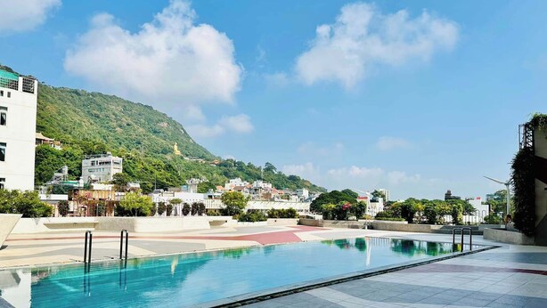A swimming pool with a view of a hillside and buildings in the background. - Petro Hotel (Ho Chi Minh City)