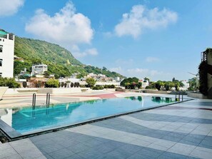 A swimming pool with a view of a hillside and buildings in the background. - Petro Hotel (Ho Chi Minh City)