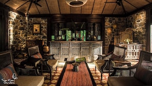 Un interior tradicional con paredes de piedra, muebles de madera y una mesa central con un libro y objetos decorativos.