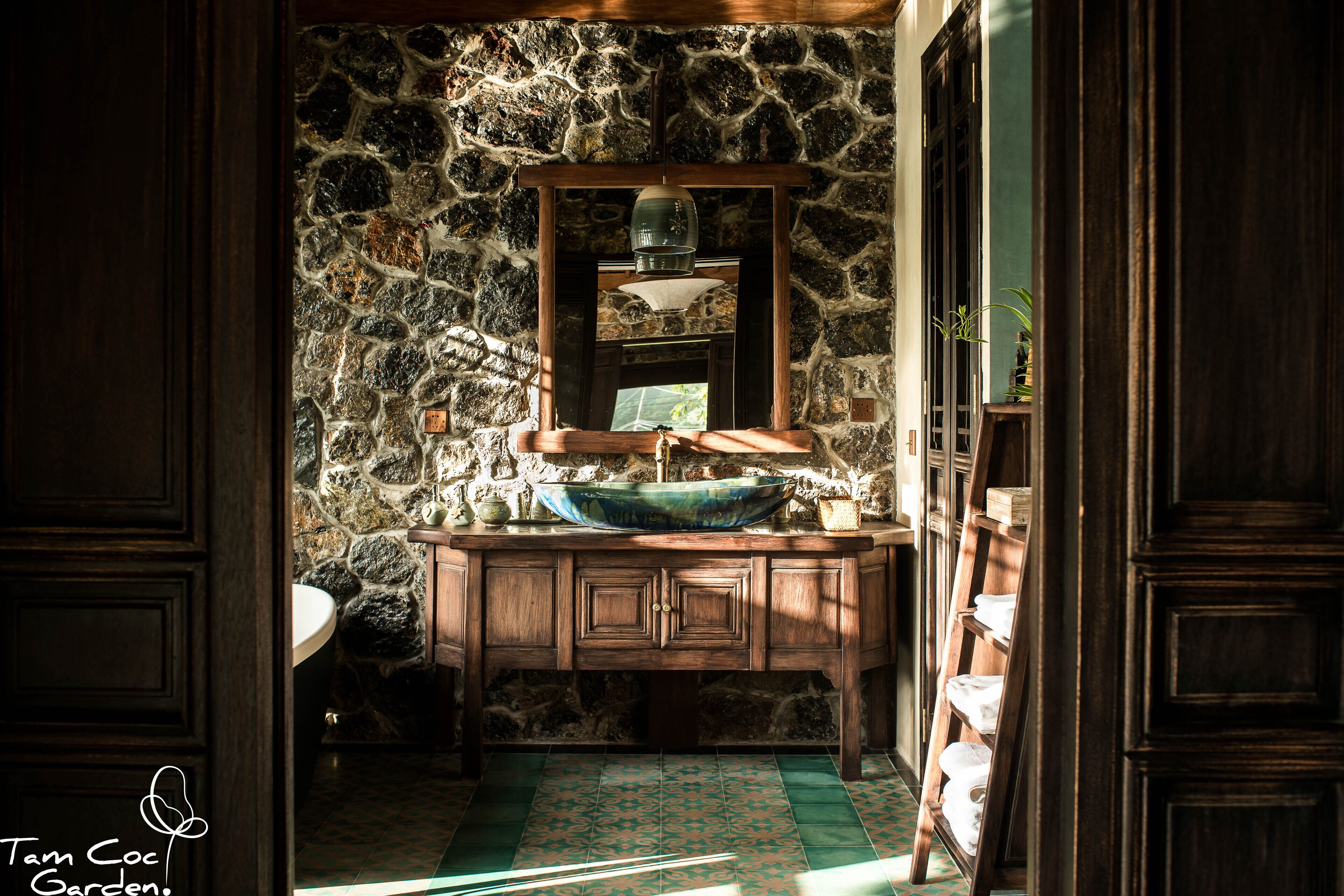 A stone wall, wooden cabinets, a sink, and a mirror.