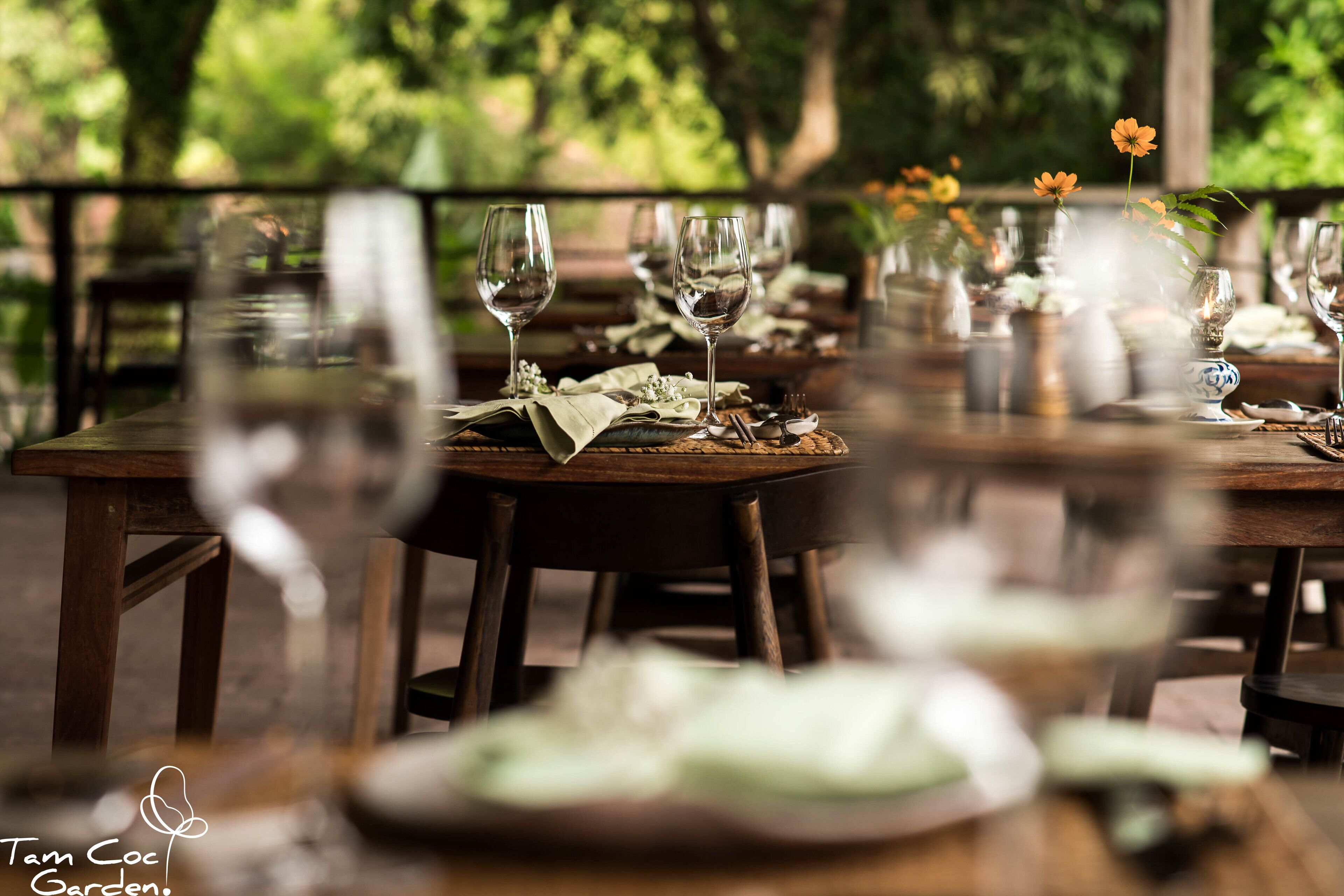 A dining table set with wine glasses, plates, and a vase with flowers.