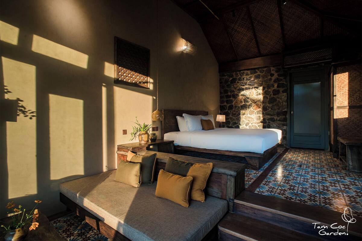 A cozy bedroom with a bed, a sofa, and a stone wall.