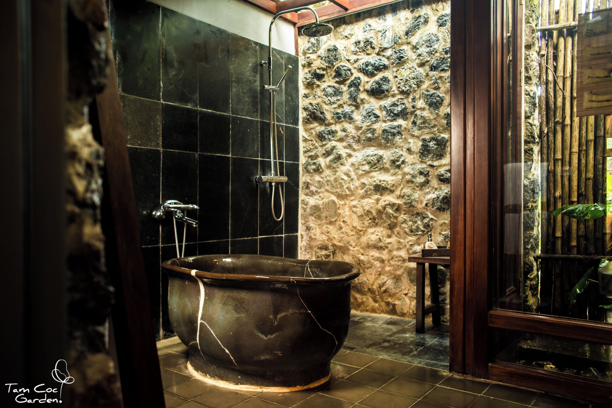 A bathroom with a freestanding bathtub, a shower, and a stone wall.
