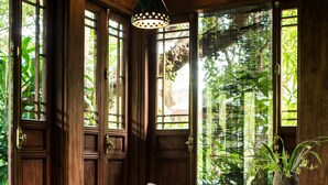 A wooden interior with a bench, a table, and a hanging light fixture. - Tam Coc Garden (Nam Hoa Lu)