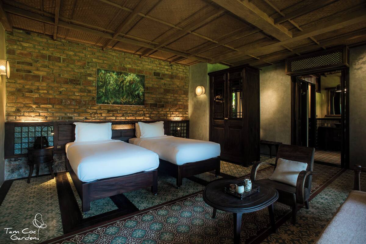 A room with two beds, a round table, and a chair.