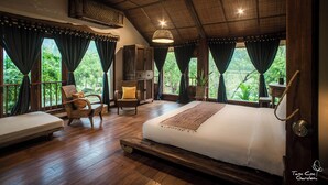 Un dormitorio amplio con una cama grande, suelo de madera y vistas a exuberante vegetación.