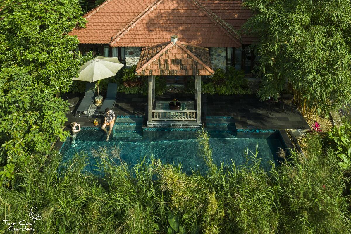 An aerial view of a swimming pool area with a gazebo, surrounded by lush greenery.