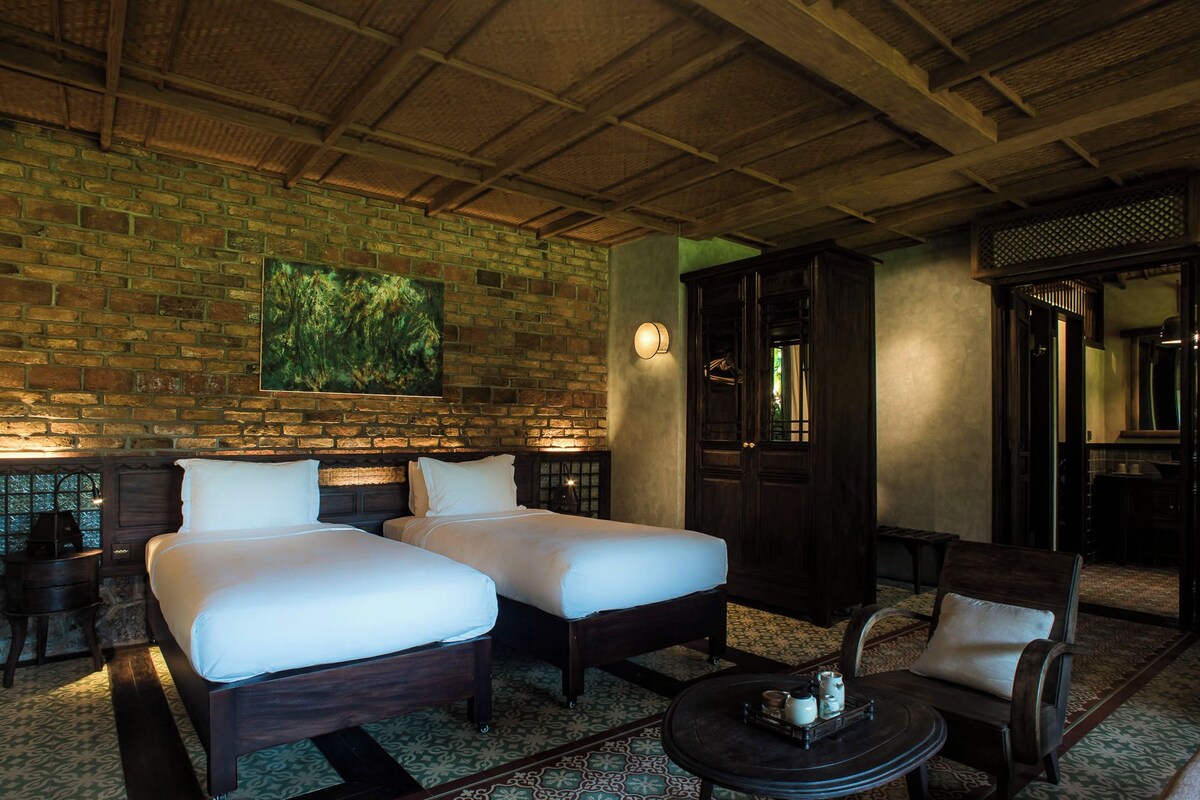 A room with two beds, a round table, and a chair.