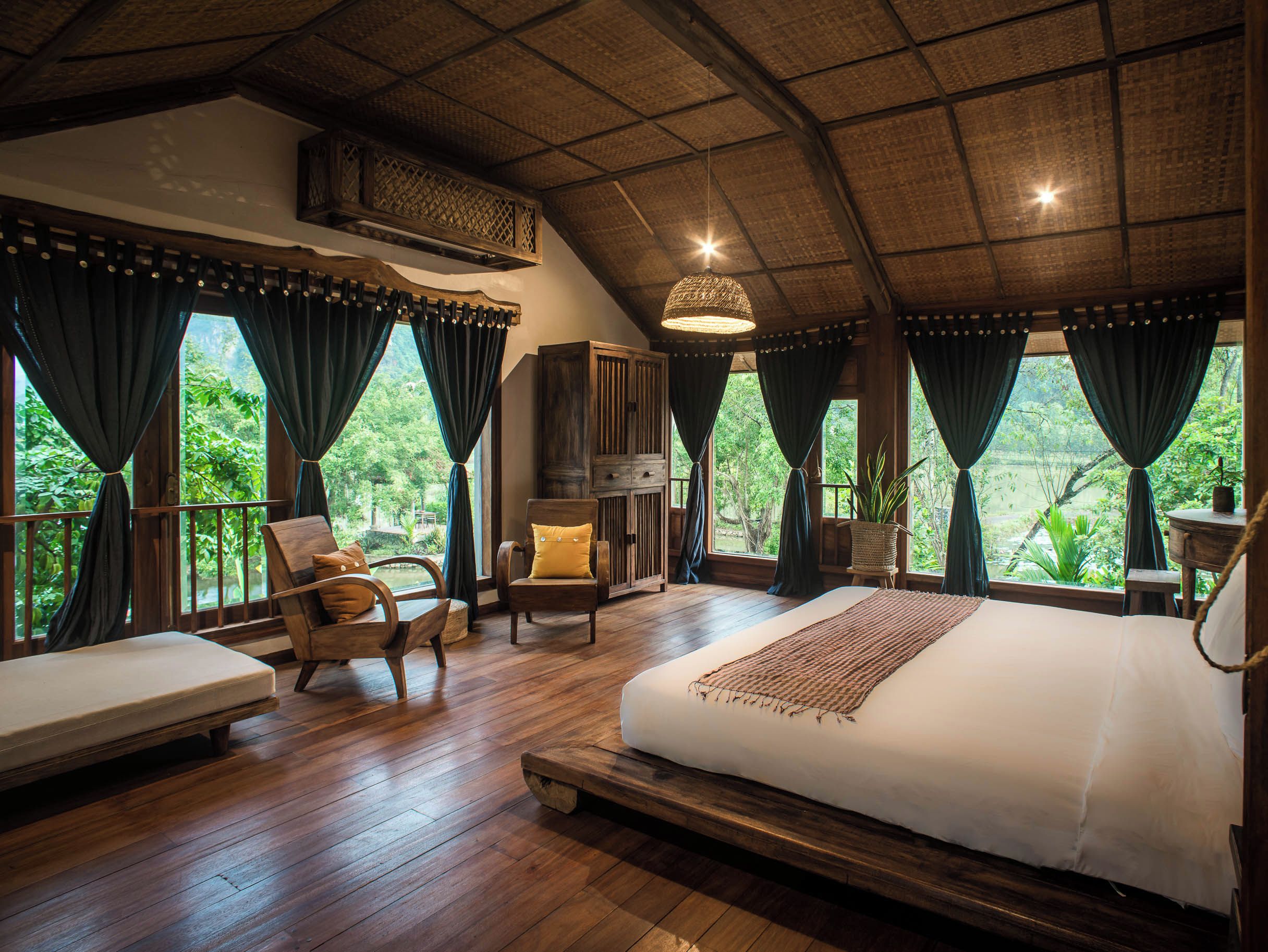 Une chambre spacieuse avec un grand lit, un plancher en bois et une vue sur une végétation luxuriante.