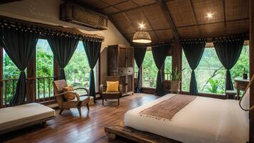 Une chambre spacieuse avec un grand lit, un plancher en bois et une vue sur une végétation luxuriante.