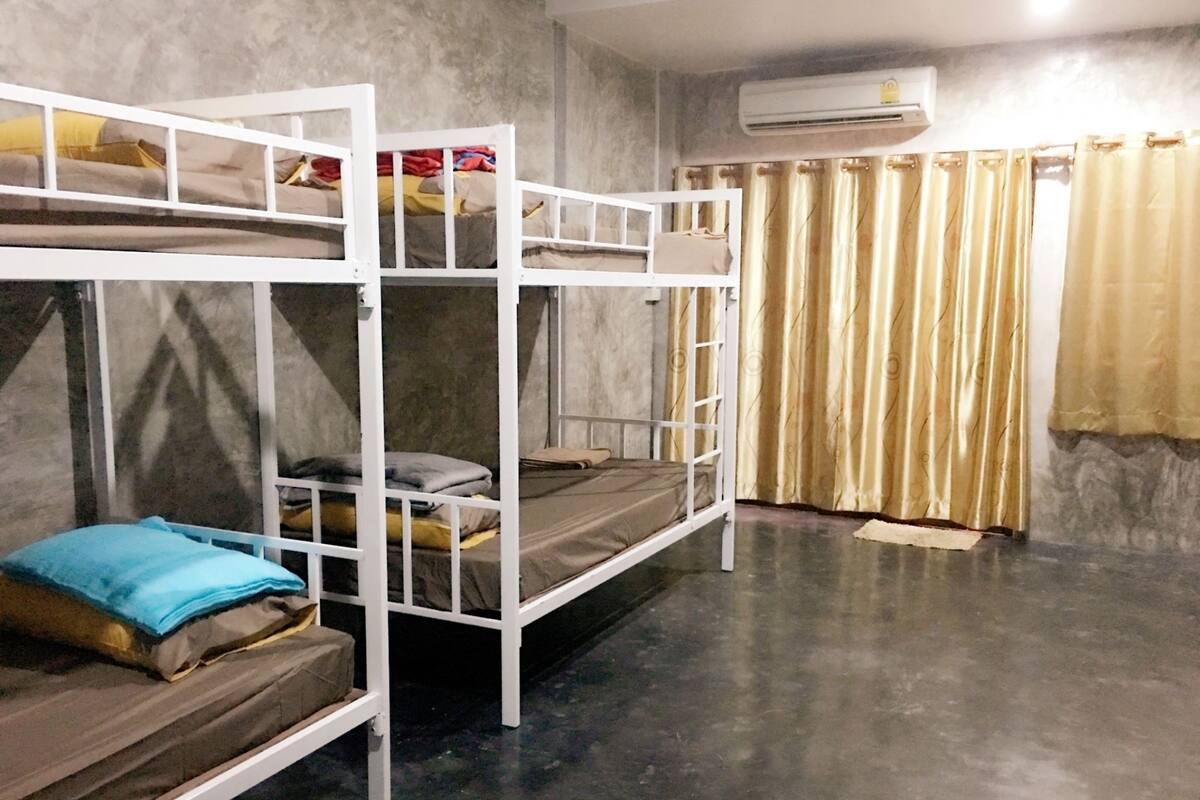 A room with bunk beds, a grey floor, and a curtain.
