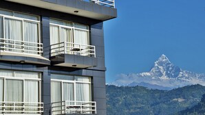 Un hôtel doté de nombreux balcons, de grandes fenêtres avec rideaux et offrant une vue sur une montagne enneigée.