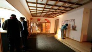 A corridor with a wooden ceiling and a person standing near a wall with a poster. - Alpine Villa Nozawa (Nozawaonsen)
